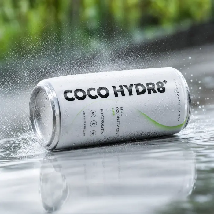 A can of COCO HYDR8 Lime rolling across a wet surface in a spray of droplets