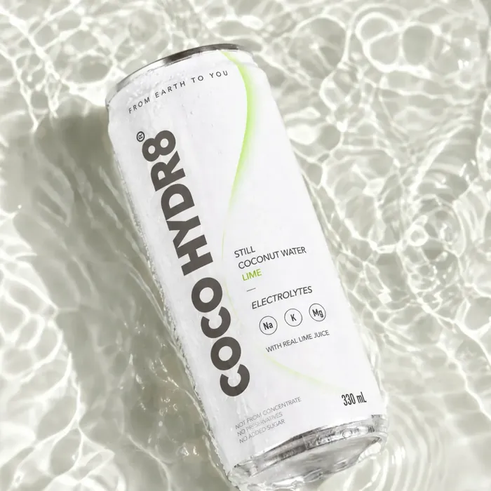 A can of COCO HYDR8 Lime lying in shallow, sunlit water