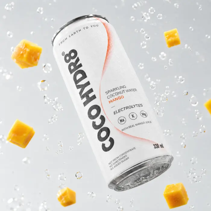 A can of COCO HYDR8 Mango floating among mango cubes and bubbles