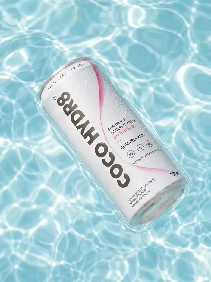 A can of COCO HYDR8 Watermelon floating in a sunlit swimming pool